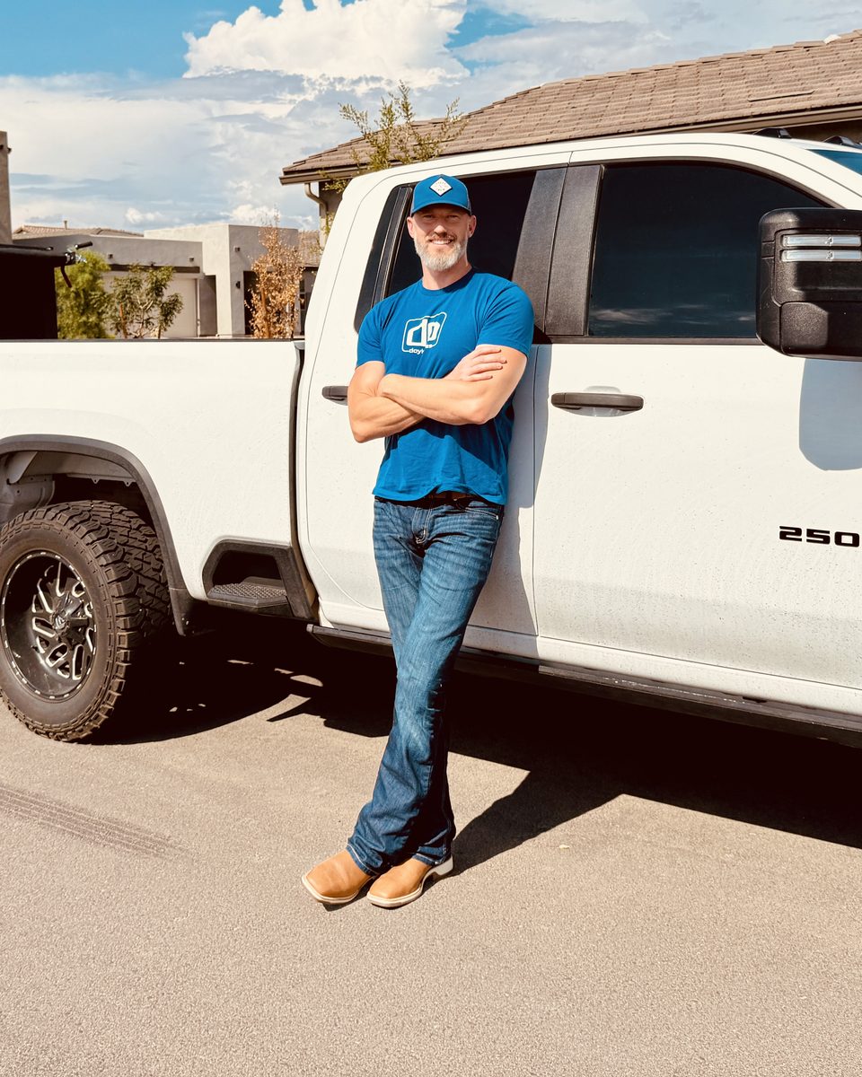 Ryan Doyle, founder of Pale Blue Lot, leaning against his white pickup truck